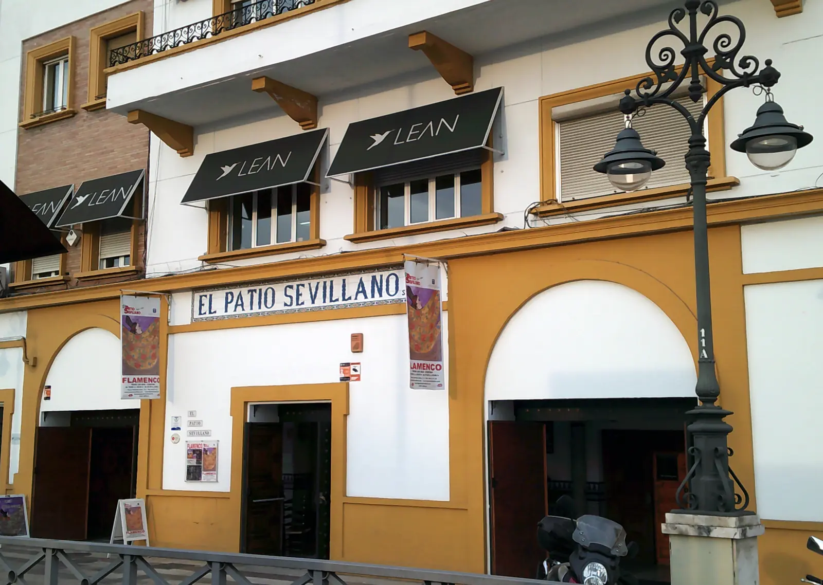 La facciata dell'edificio sul Paseo de Cristóbal Colón, con un'insegna in piastrelle blu con la scritta El Patio Sevillano sopra due portali ad arco