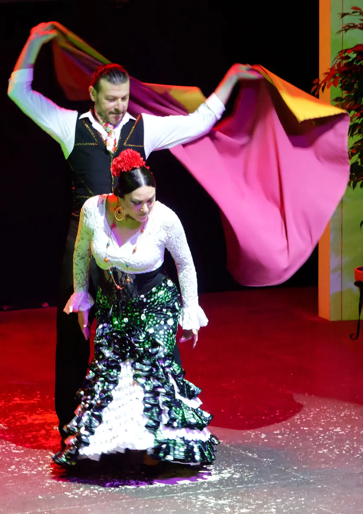 Una ballerina in abito nero a pois e una ballerina in camicetta bianca e gonna con volant si esibiscono insieme su un palco illuminato di rosso